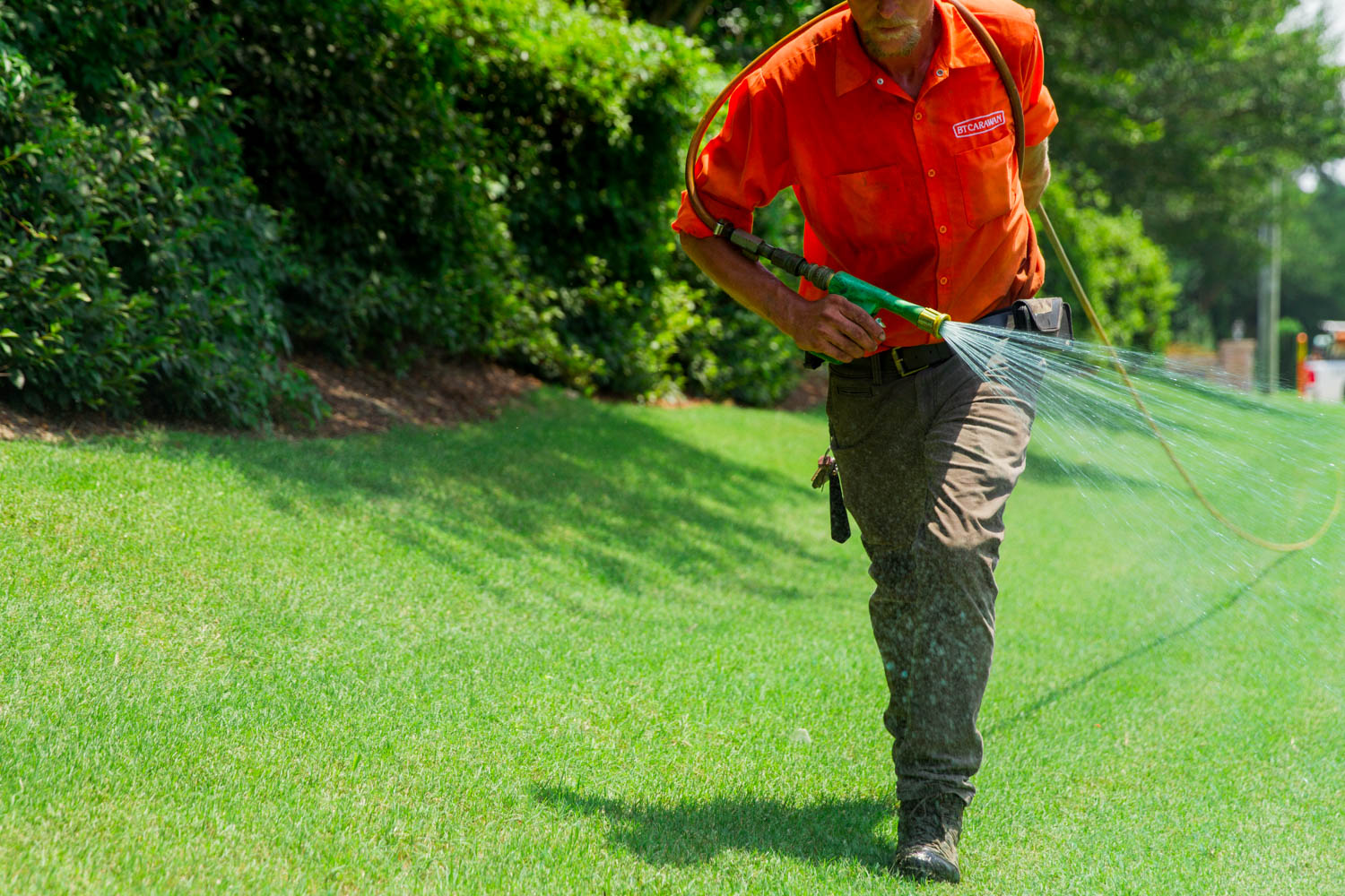 Crew member tending turf with a hose